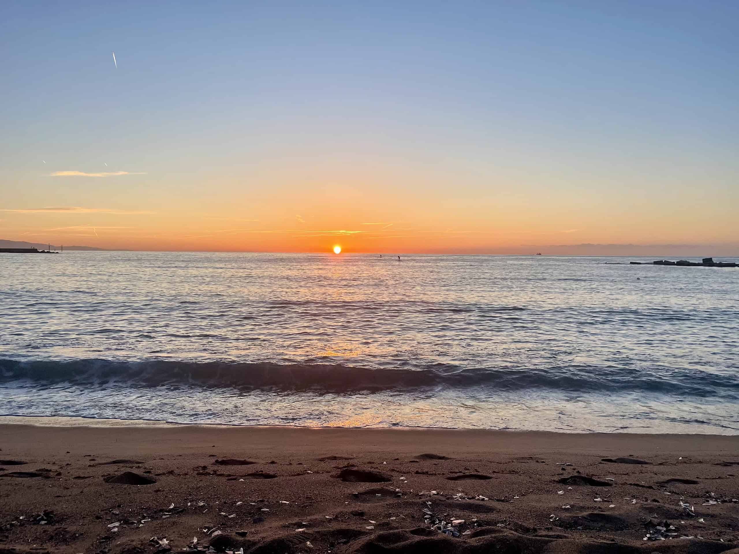 Ola de calor: las 5 estrategias de los españoles para sobrevivir al calor 9 Puesta de sol en Barcelona, vista del mar Mediterráneo al amanecer, con cielos despejados y un ambiente tranquilo, que representa la belleza natural de la ciudad temprano en la mañana.