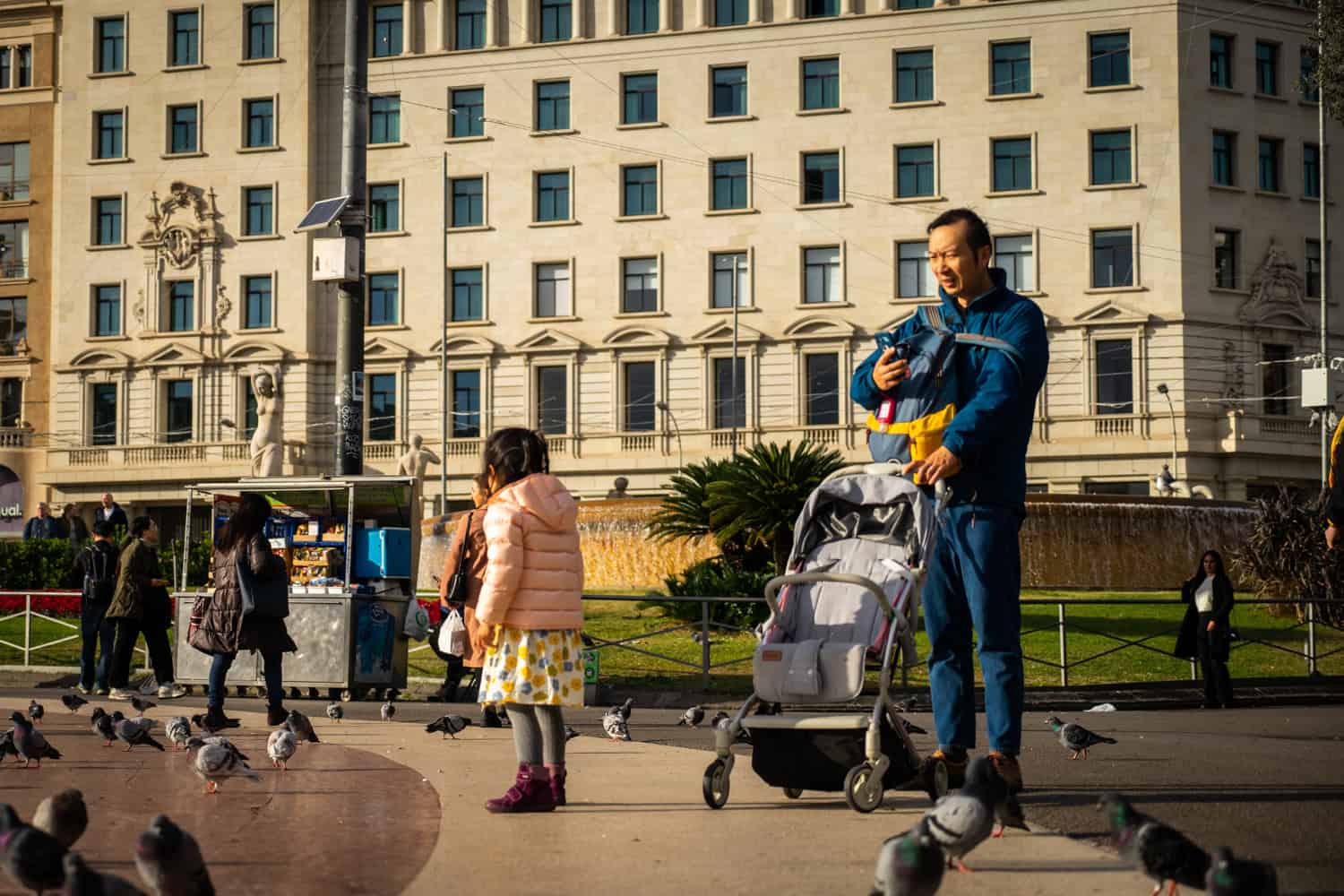 Familia padre niño cochecito Plaça Catalunya palomas foto Clementine Laurent