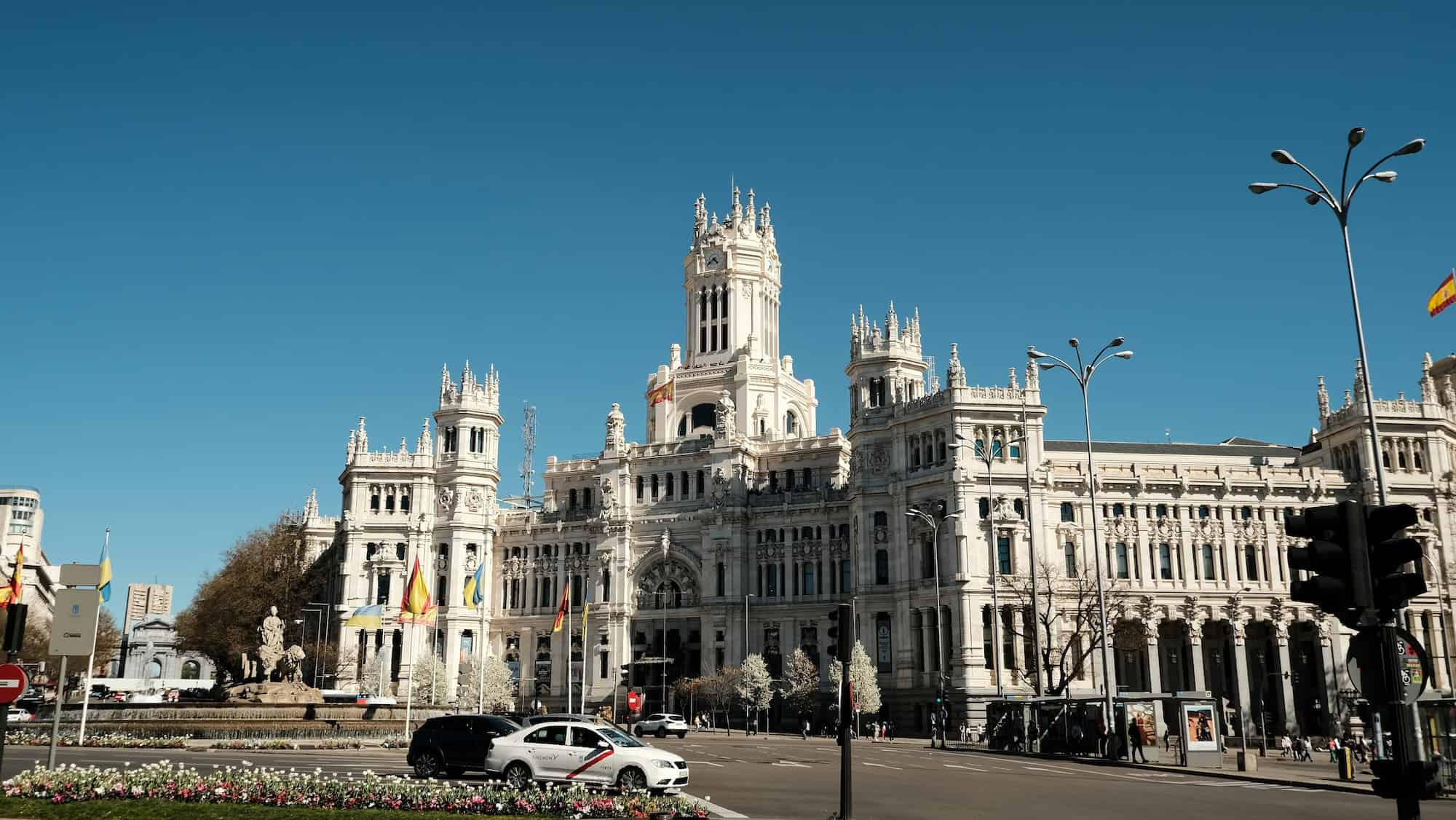 Caminando frente al histórico ayuntamiento de Madrid bajo un cielo azul despejado.