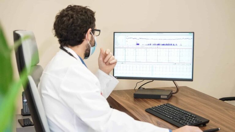 Cardiólogo analizando datos en un ordenador en una consulta de cardiología de Barcelona, ​​especializada en atención cardíaca a pacientes francófonos.